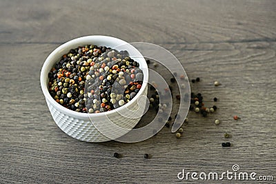 A mixture of pepper varieties with peas on the white plate on the wooden background. Heap of various pepper. Mix of red Stock Photo