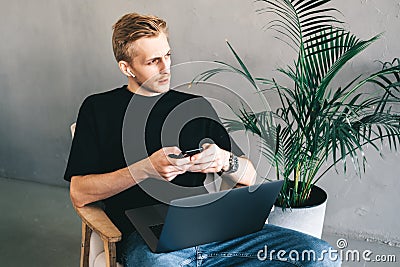 Mman mobile developer in earphones using smartphone, testing application Stock Photo