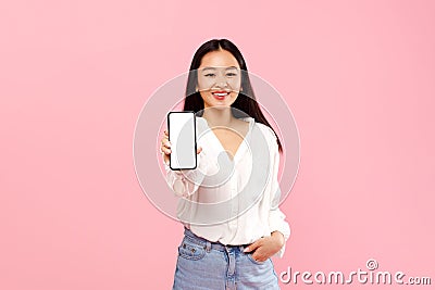 Mobile app ad. Happy asian lady showing white empty smartphone screen, recommending application or website, mockup Stock Photo