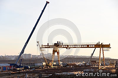 Mobile auto cranes and gantry crane working at construction site. Stock Photo