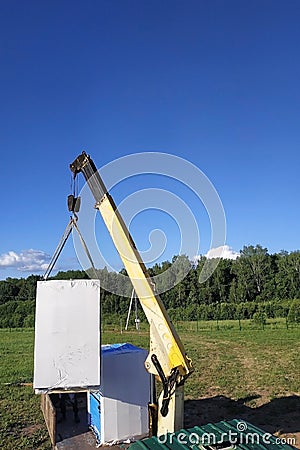 The mobile crane unloads pallets of blocks from the trailer of the truck Stock Photo