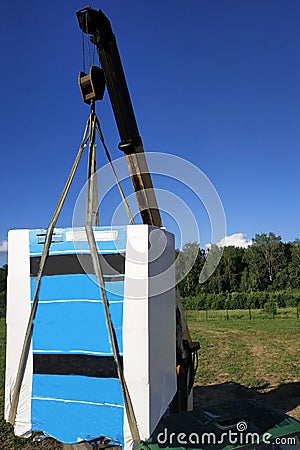 The mobile crane unloads pallets of blocks from the trailer of the truck Stock Photo