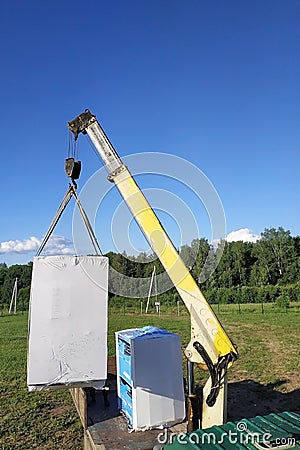 The mobile crane unloads pallets of blocks from the trailer of the truck Stock Photo