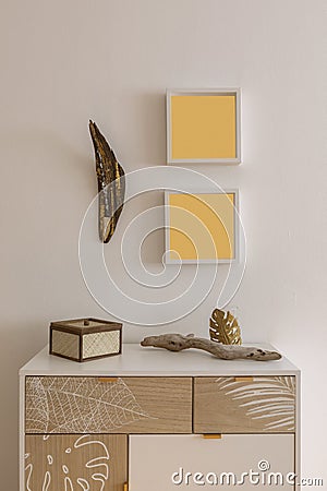 Mobile detail with drawers and various objects placed on top. Above the cabinet there are two empty frames Stock Photo