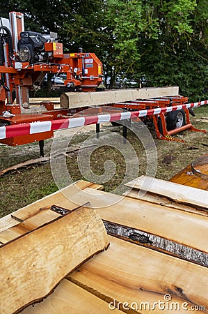 Mobile industrial sawing machine on a truck trailer in operation when sawing logs, in the foreground are sawn boards on a pile Stock Photo