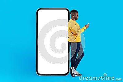 Mobile Mockup. Young Blank Man With Smartphone Standing Near Big Blank Telephone Stock Photo