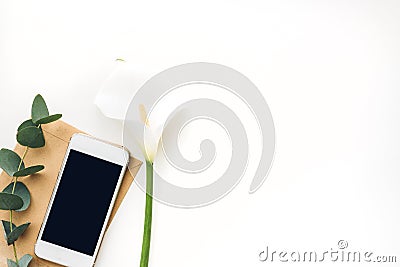 Mobile phone with blank screen and flowers on white background, top view. mock up Stock Photo