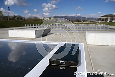 Mobile phone charging remotely on a solar bench Stock Photo