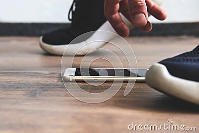 The mobile phone fell to the ground and the man bent over for it Stock Photo