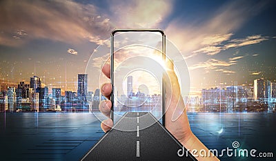 Creative design with mobile phone in hand, road coming out of smartphone with city skyline background. Stock Photo