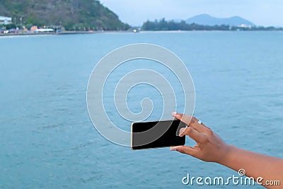 Mobile phone in hand with sea Stock Photo