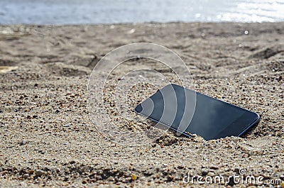 Mobile phone lying on the beach in the sand. weatherproof phones, lost phone concept Stock Photo