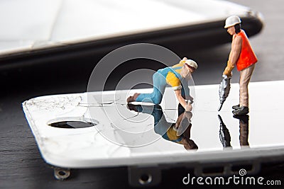 Mobile phone repair service concept. Miniature technician people repairing a cracked smart phone screen. Close up image. Stock Photo