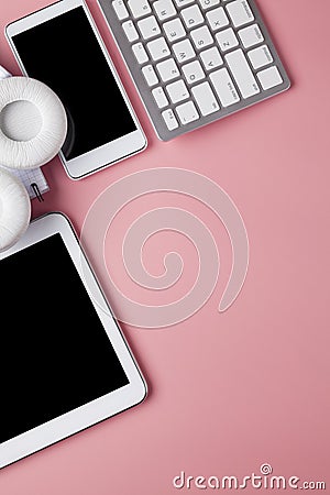 Mobile phone, tablet, computer keyboard, headphones and notebook on pink background Stock Photo