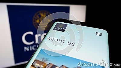 Mobile phone with webpage of British housebuilding company Crest Nicholson plc on screen in front of logo. Editorial Stock Photo
