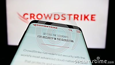 Mobile phone with website of cybersecurity company CrowdStrike Holdings Inc. on screen in front of logo. Editorial Stock Photo