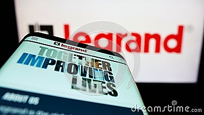 Mobile phone with website of French electronics company Legrand S.A. on screen in front of business logo. Editorial Stock Photo