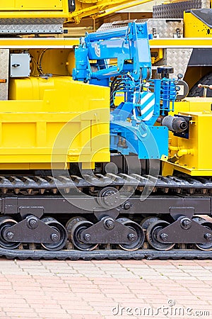 A blue hydraulic crane on a yellow crawler mobile construction platform Stock Photo