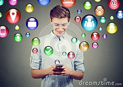 Mobile technology high tech concept. Happy young man using smart phone with social media application icons flying out of screen Stock Photo