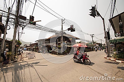 A mobile Walls ice creams seller passes a quiet crossing on her motorbike in Pai. Editorial Stock Photo