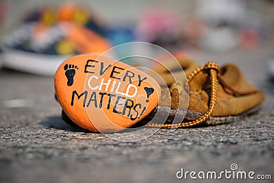 Moccasin and painted orange rock left in memory of aboriginal children Editorial Stock Photo