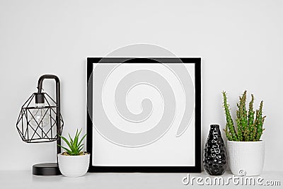 Mock up black square frame with home decor and potted plants with white shelf and wall Stock Photo