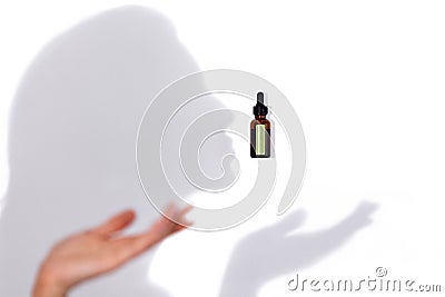 Mock up of brown glass serum or oil bottle with pipette and green stiker and shadows like silhouette of female profile and her Stock Photo