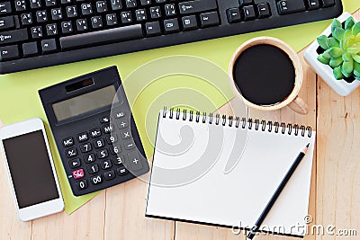 Mock up of office table desk workspace with blank notebook, smart phone, calculator, computer keyboard and coffee Stock Photo