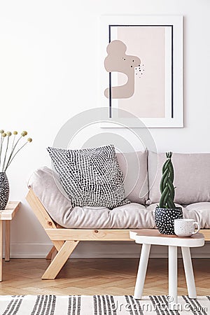 Mock-up painting on a white wall of an artistic living room interior with simple, wooden furniture and patterned decorations Stock Photo