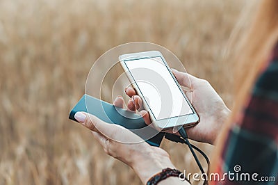 Mock Up of the phone and the bank in the hand of a girl, against the background of a yellow field. Stock Photo