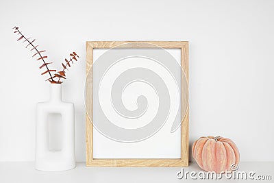 Mock up portrait wooden frame with autumn decor on a white shelf against a white wall Stock Photo