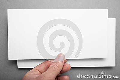 Mock up of white DL flyer on a grey background in hand Stock Photo