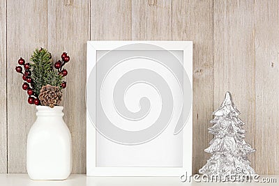 Mock up white frame with Christmas branches and silver tree on a shelf against a rustic gray wood wall Stock Photo