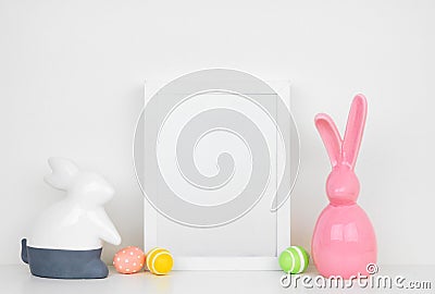 Mock up white frame with Easter Eggs and modern Easter bunny decor on a shelf Stock Photo