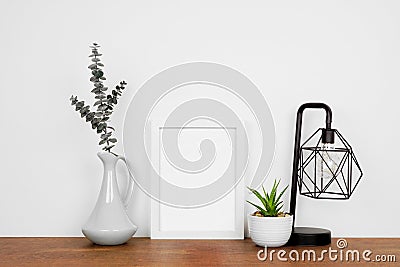 Mock up white portrait frame with home decor and potted plant on a wood shelf against a white wall Stock Photo