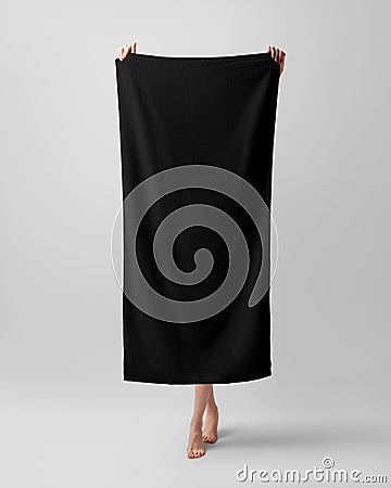 Mockup of a black towel, a girl holds a full-length bath towelette, isolated on a white background in the studio Stock Photo