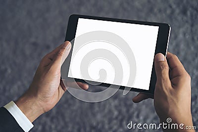 Mockup image of a business man sitting and holding black tablet pc with blank white screen with gray rug Stock Photo