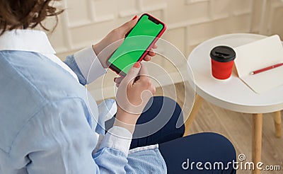 Mockup image: girl in in blue shirt and trousers holding black mobile phone with chroma key screen Stock Photo