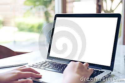 Hand using laptop with blank white screen on vintage wooden table in cafe Stock Photo