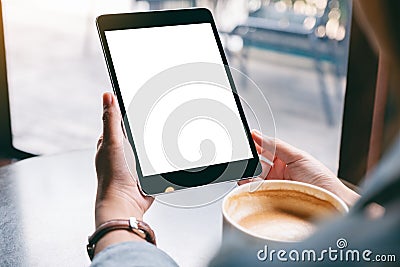 A woman holding black tablet with white blank screen and coffee cup on the table Stock Photo