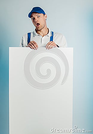 Mockup image of a young indignant worker holding empty white banner. White or blue background. Bussines concept Stock Photo