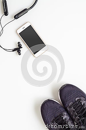 Mockup mobile cellphone with wireless bluetooth earphone and running shoes on white background. Healthy active lifestyles Stock Photo
