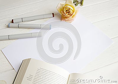 Mockup for A4 paper with single rose, book and drawing material Stock Photo