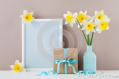 Mockup of picture frame decorated narcissus or daffodil flowers in vase and gift box for greeting on mother day. Stock Photo