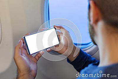 Mockup smartphone airplane. Young attractive european man holding blank screen smartphone in hands in airplane. Mock up for a game Stock Photo