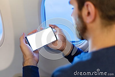 Mockup smartphone airplane. Young attractive european man holding blank screen smartphone in hands in airplane. Mock up for a game Stock Photo