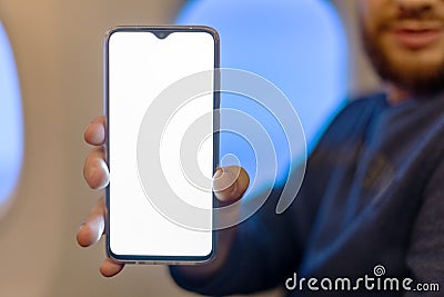 Mockup smartphone airplane. Young attractive european man holding blank screen smartphone in hands in airplane. Mock up for a game Stock Photo