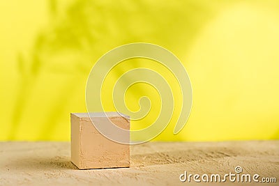 Mockup. Textured cube of beige surface on a yellow background with shadows from plants Stock Photo