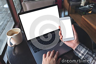 Mockup top view image of business woman holding white mobile phone with blank screen with laptop and coffee cup on wooden table Stock Photo
