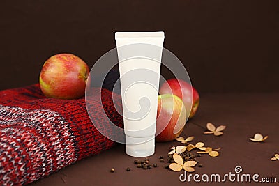 Mockup of white squeeze bottle plastic cosmetic tube for branding, red apples, Christmas or autumn red knitted sweater, dry Stock Photo